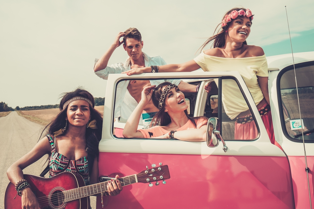 Amigos hippies multiétnicos con guitarra en un viaje por carretera