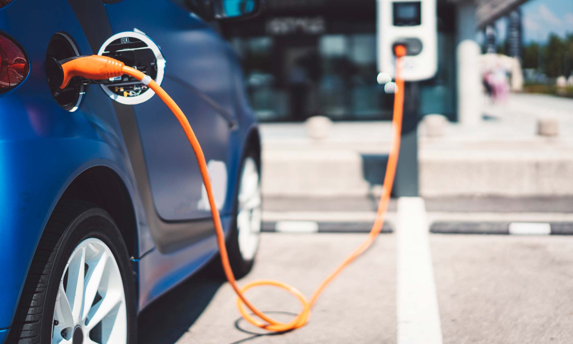 Un vehículo eléctrico conectado a una estación de carga al aire libre.