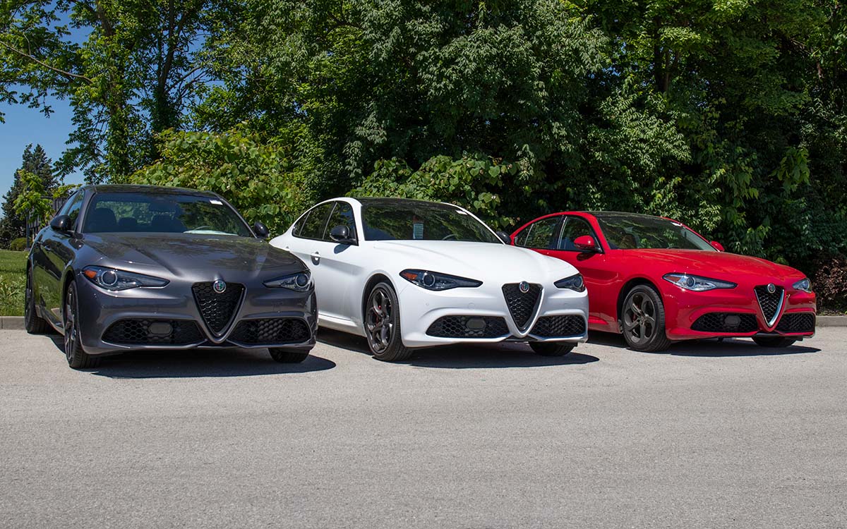Una fila de tres vehículos Alfa Romeo Giulia en gris, blanco y rojo.
