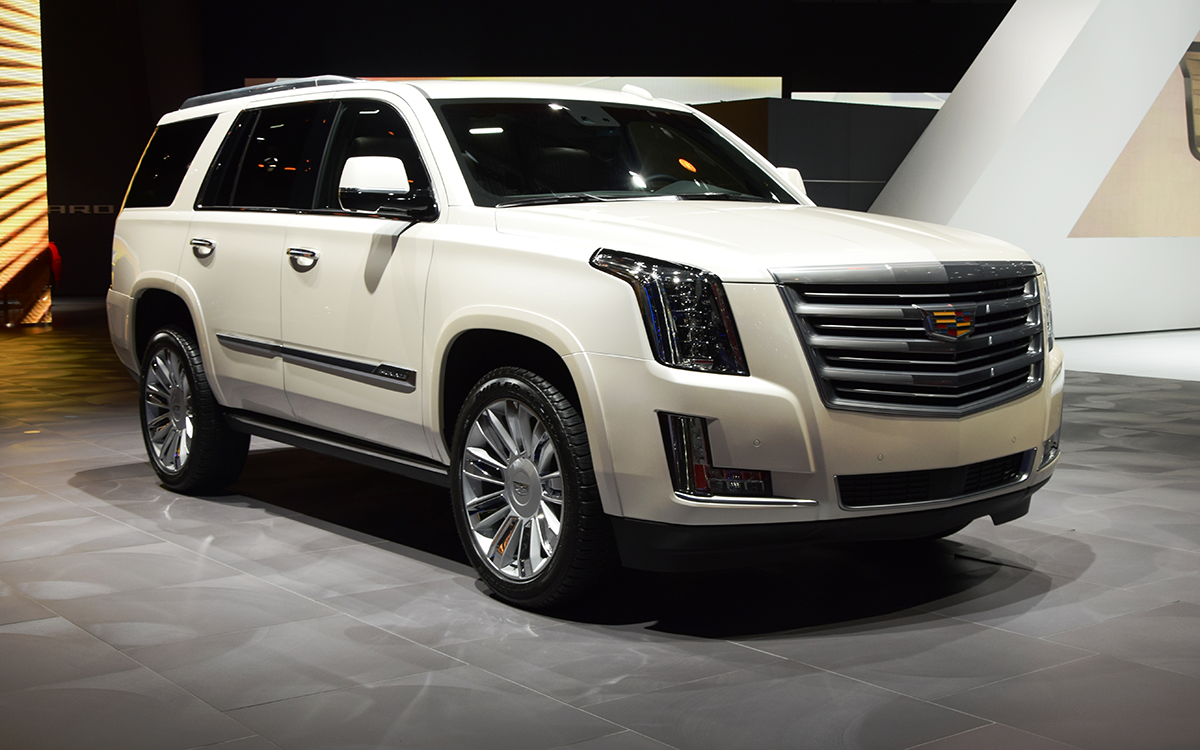 Un Cadillac Escalade blanco 2015 en exhibición en un salón del automóvil.