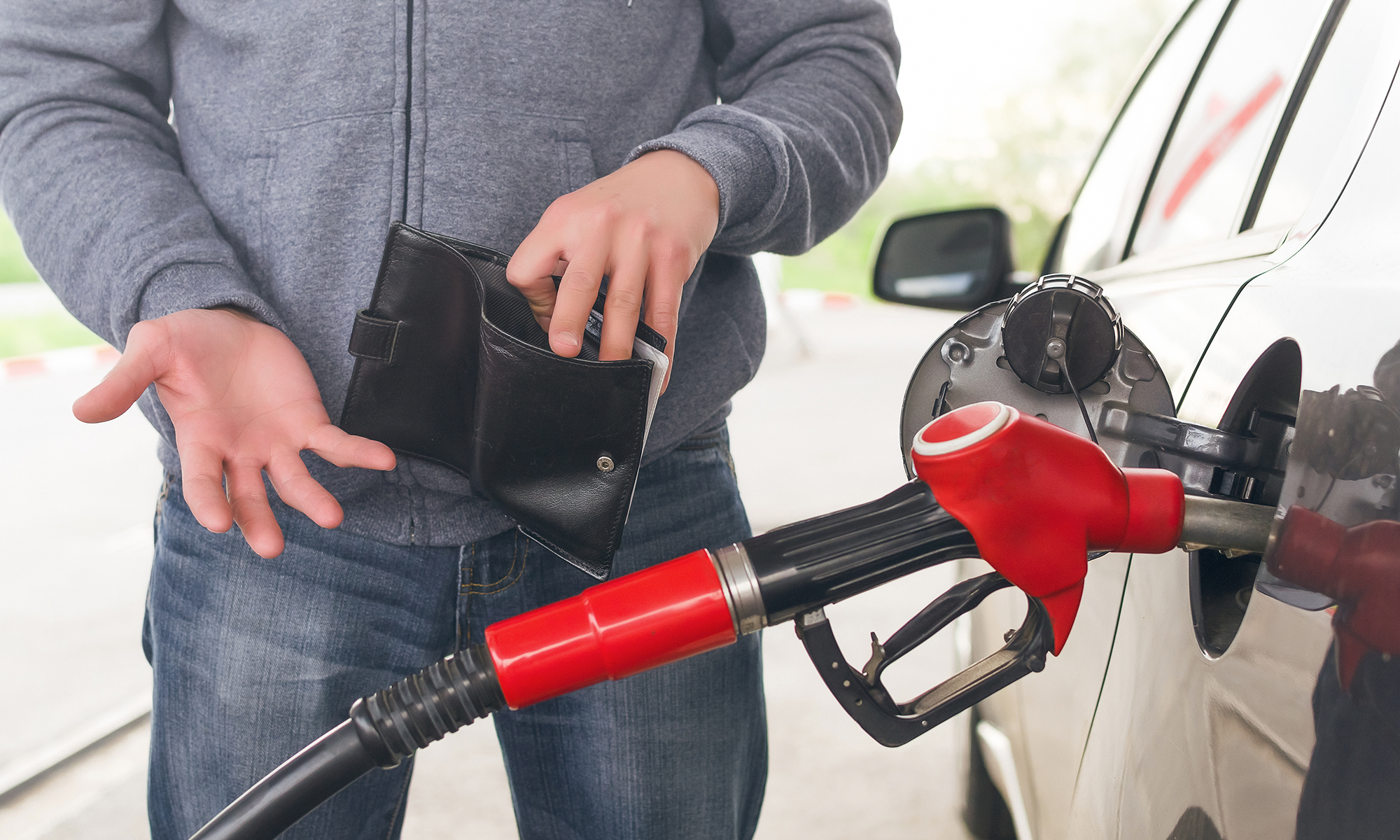 Un hombre muestra una billetera vacía mientras carga gasolina. Pero al igual que tener un plan de protección automotriz con garantía Endurance para ahorrar en reparaciones, saber cómo mejorar el consumo de combustible de su auto también puede ayudarle a ahorrar.