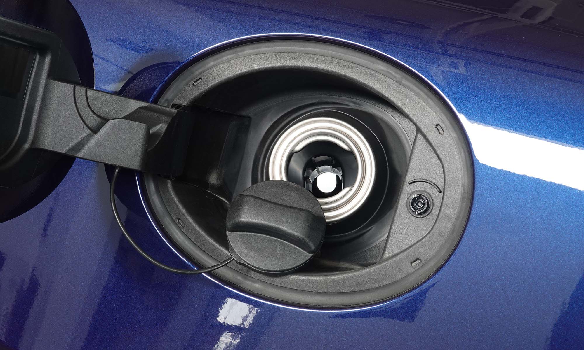 Una imagen de cerca de una tapa de gasolina abierta de un automóvil azul.