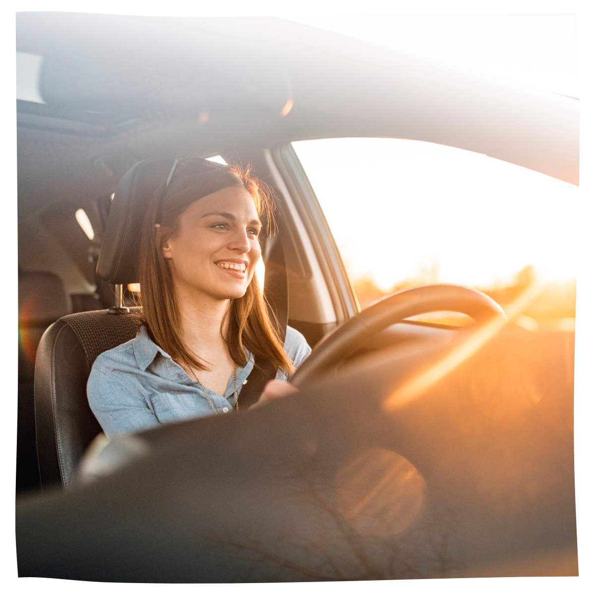 A woman in a car, driving, smiling and looking out the window