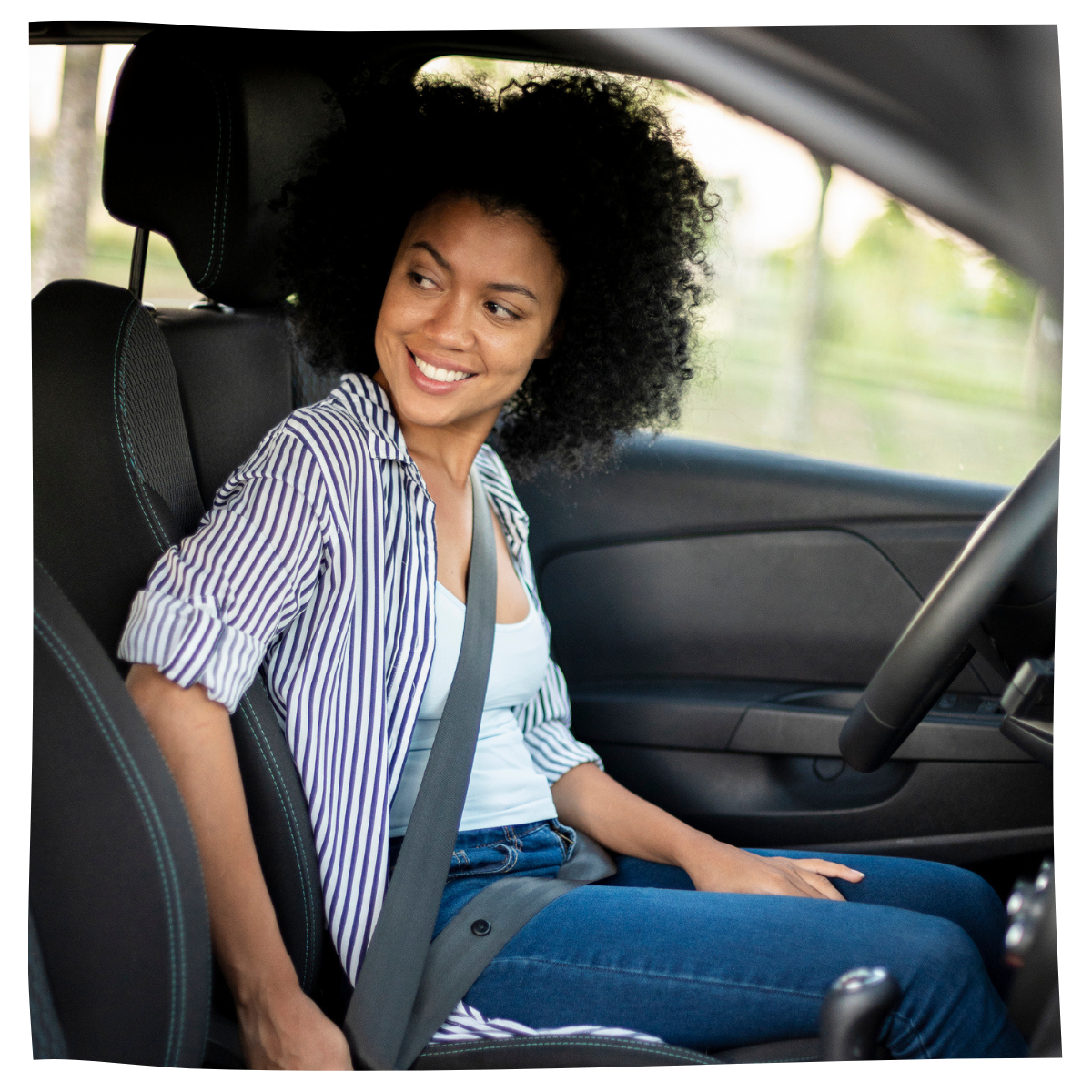Smiling young woman securing seat belt before driving car