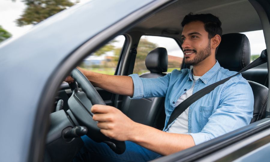 Hombre conduciendo su coche y sonriendo