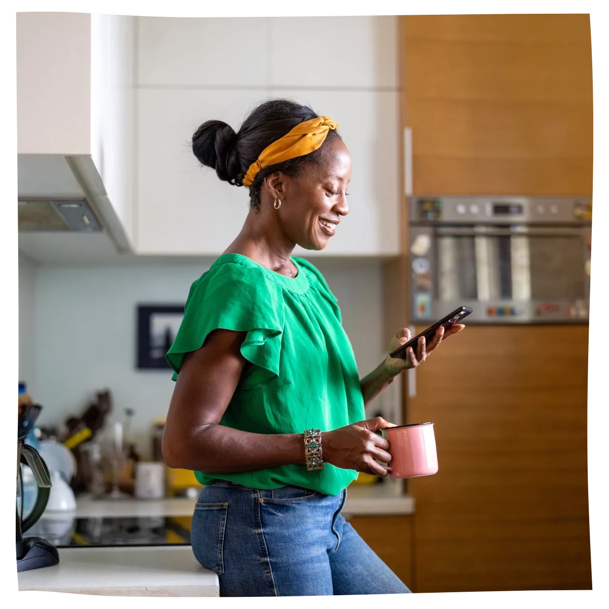 A woman looking at her smartphone in the kitchen