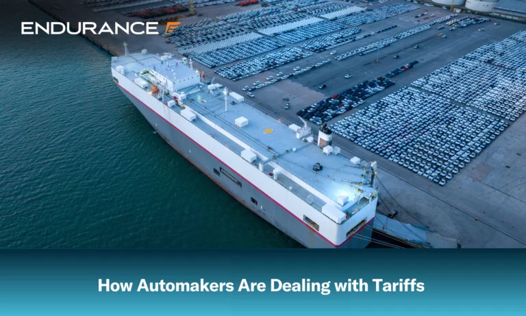 Many new cars line up near a cargo ship at sea