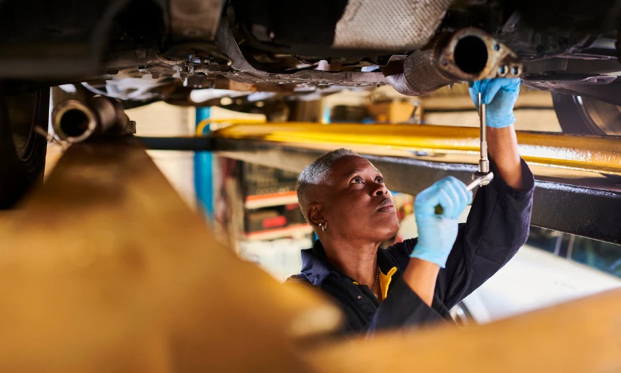 Mecánica de automóviles femenina trabajando debajo de un vehículo elevado