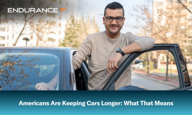 A man with glasses standing up and leaning out his drivers side door