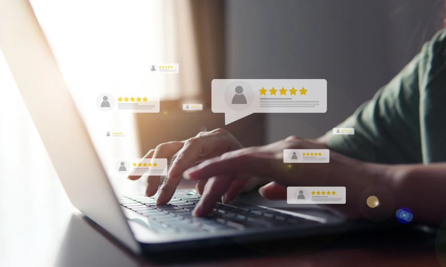 Manos escribiendo en una computadora portátil con burbujas de revisión de 5 estrellas apareciendo