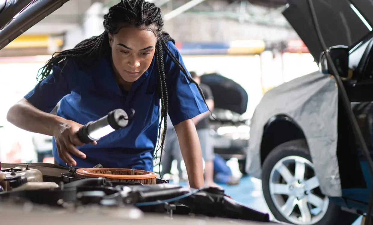 Mechanic inspecting inside of a vehicle's hood