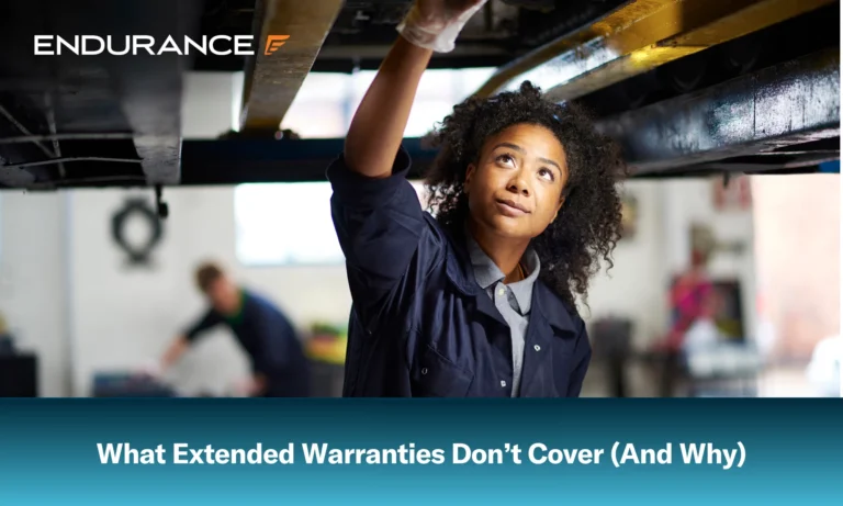 Young female adult mechanic standing under a car in a garage
