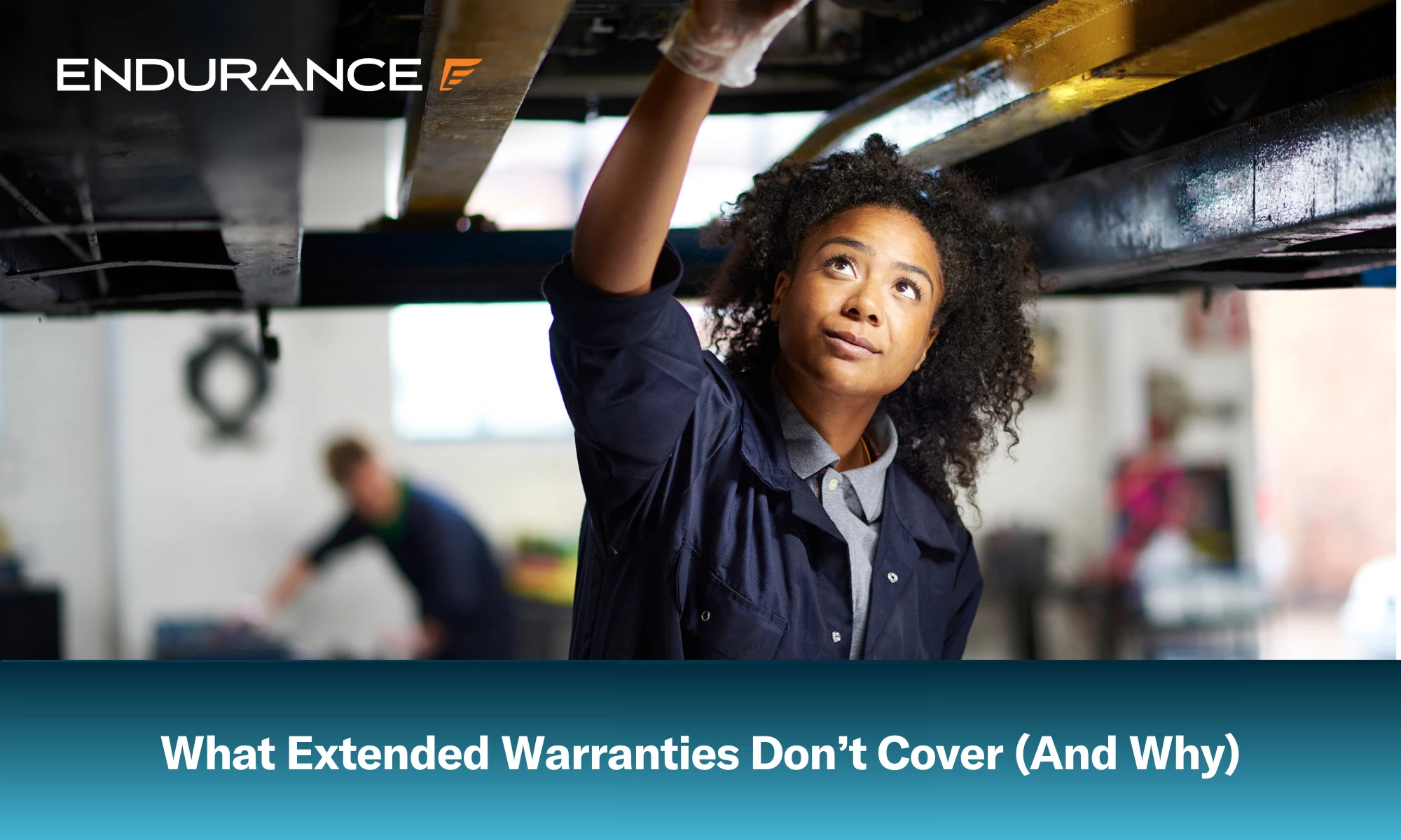 Young female adult mechanic standing under a car in a garage