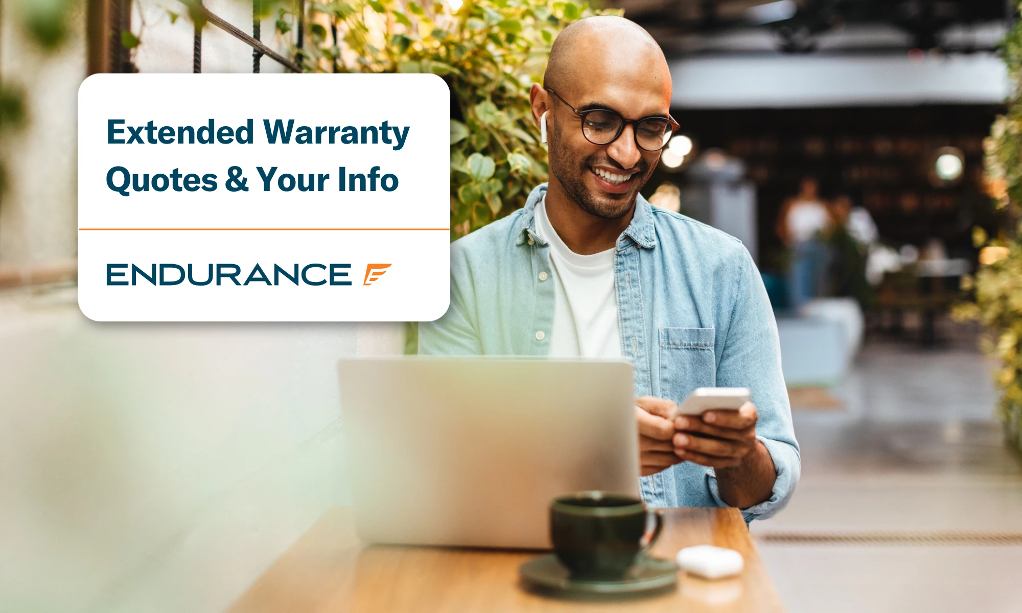 Man using a smartphone and laptop in a cafe, getting an extended warranty quote