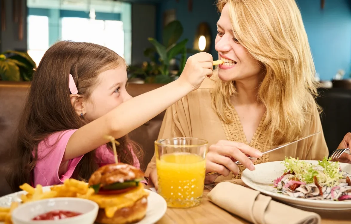 Hija alimenta a su madre con papas fritas en un restaurante.