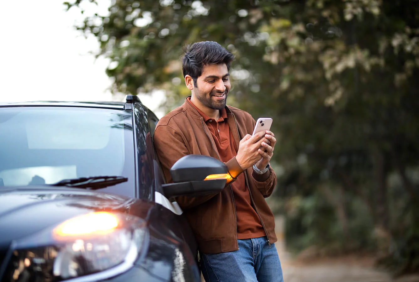 Hombre sonriendo mientras llama para pedir asistencia en carretera