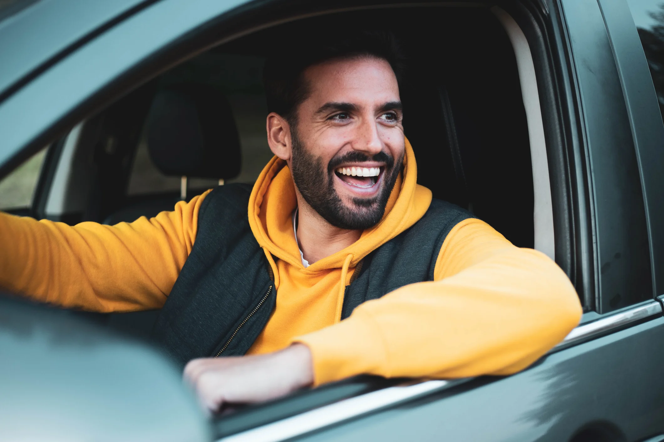 Hombre sonriendo mientras está sentado dentro de su coche.