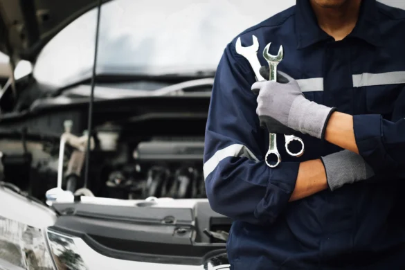 Mechanic Holding Wrenches In Front Of Car With Open Hood