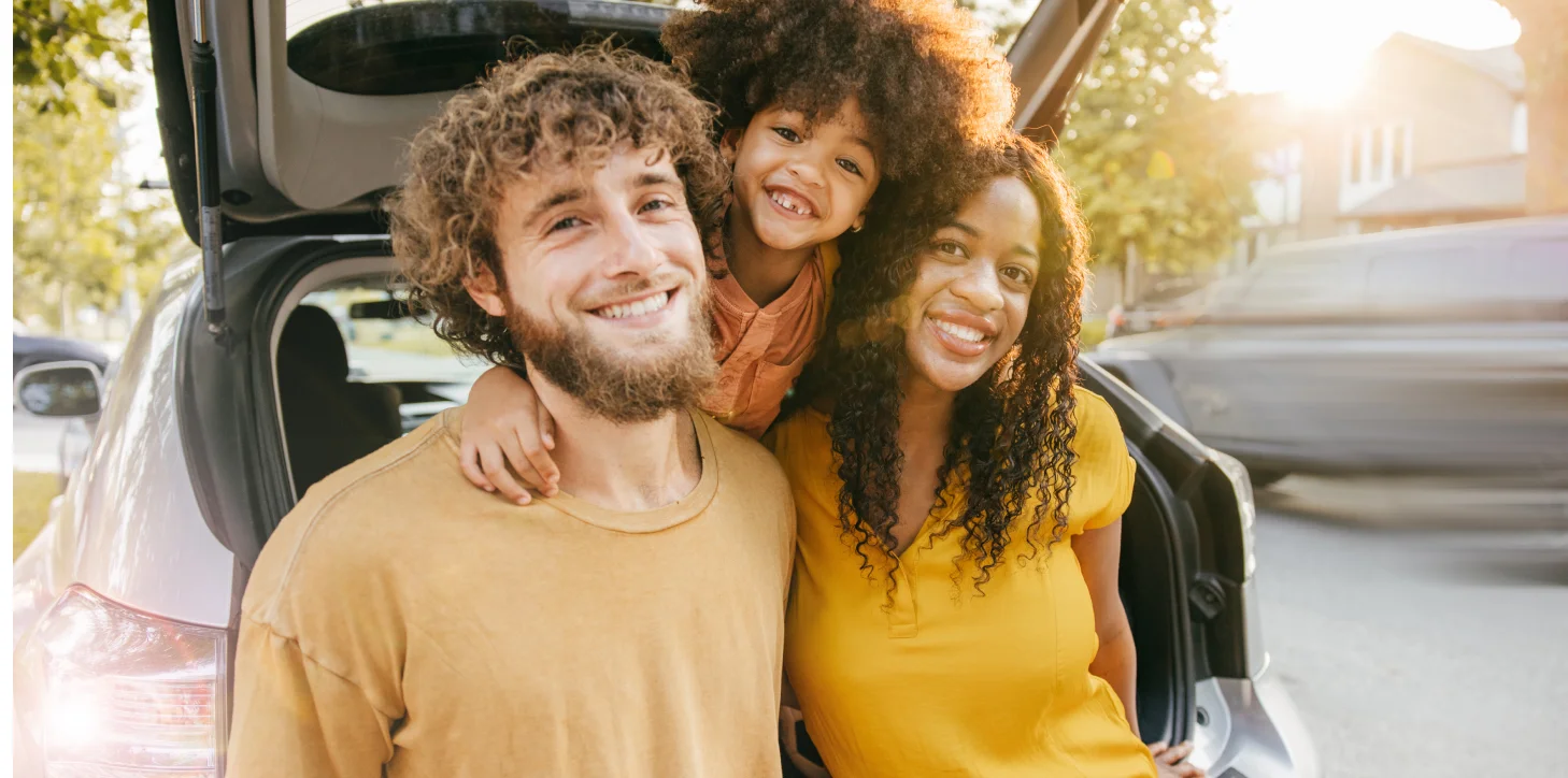 Smiling Family Standing Behind SUV