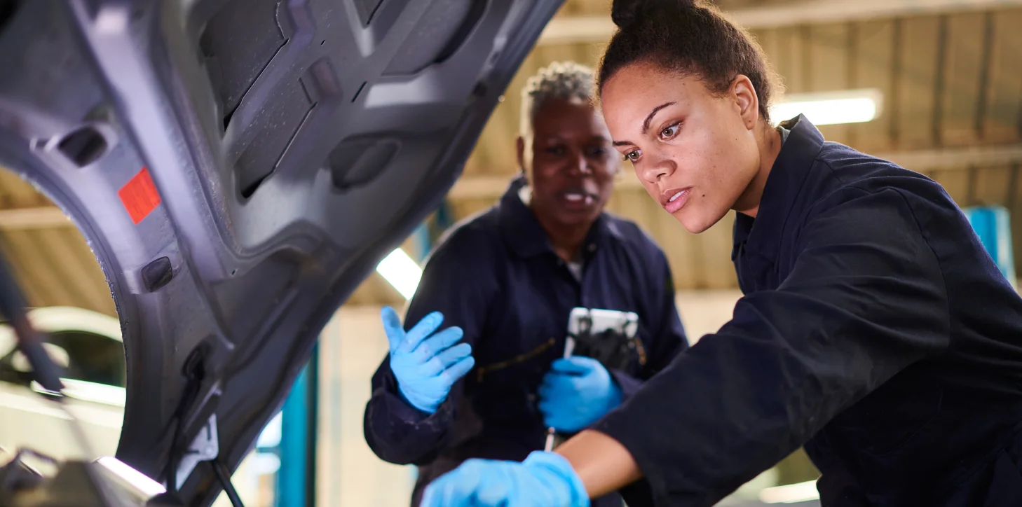 Two Female Mechanics Working Inside Car Hood